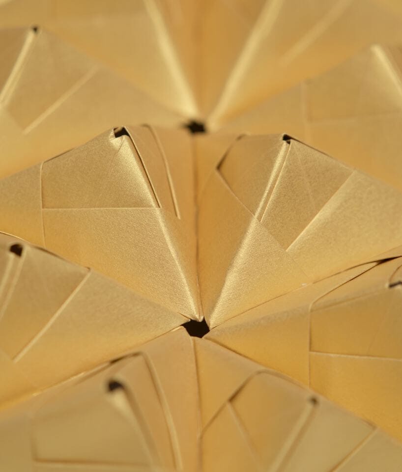 Estructura modular de papel dorado con formas triangulares repetidas en relieve, diseño geométrico de Cartoncita
