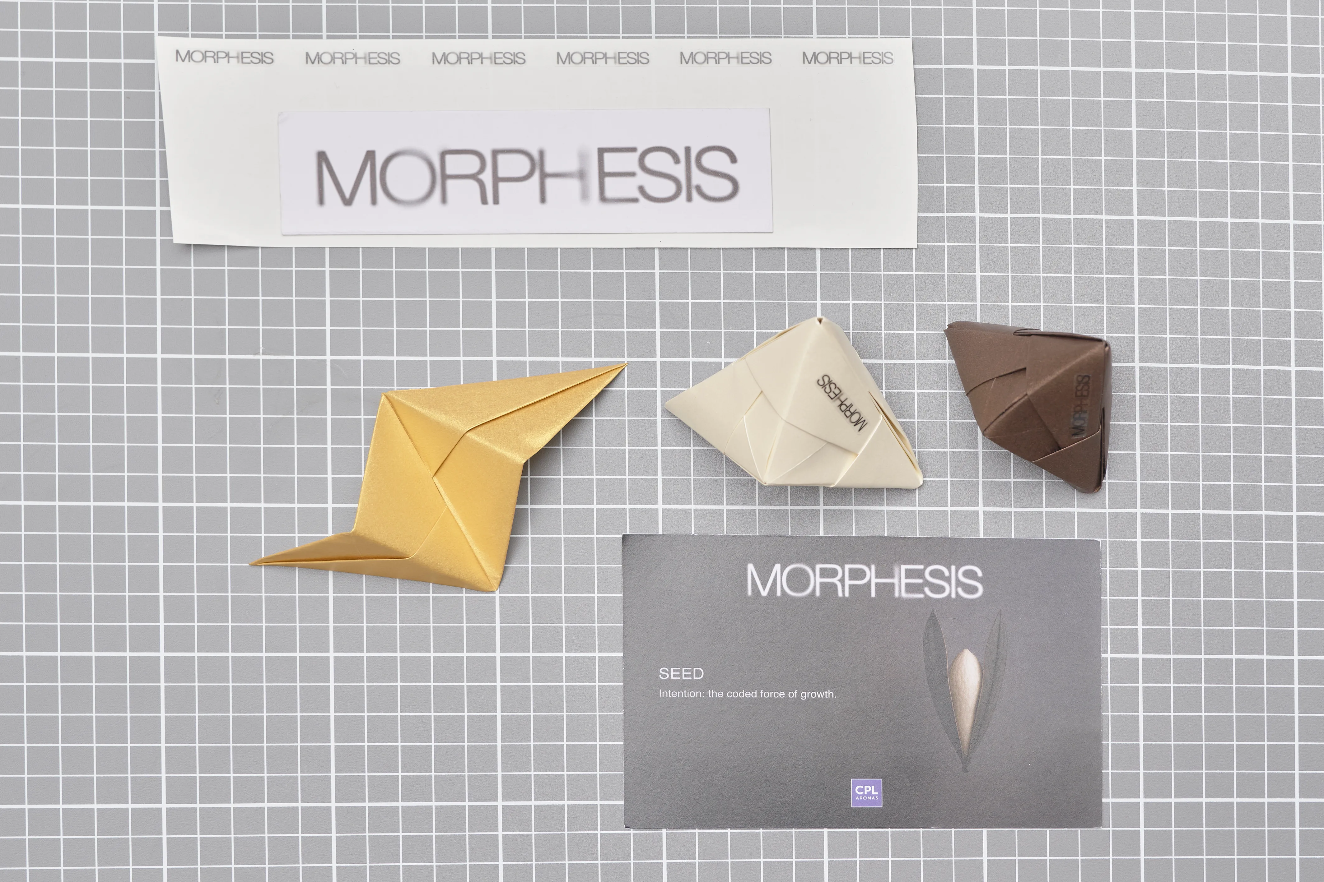 Composición de piezas de papel plegado en tonos dorado, blanco y marrón junto a material impreso sobre una mesa de corte, trabajo de Cartoncita