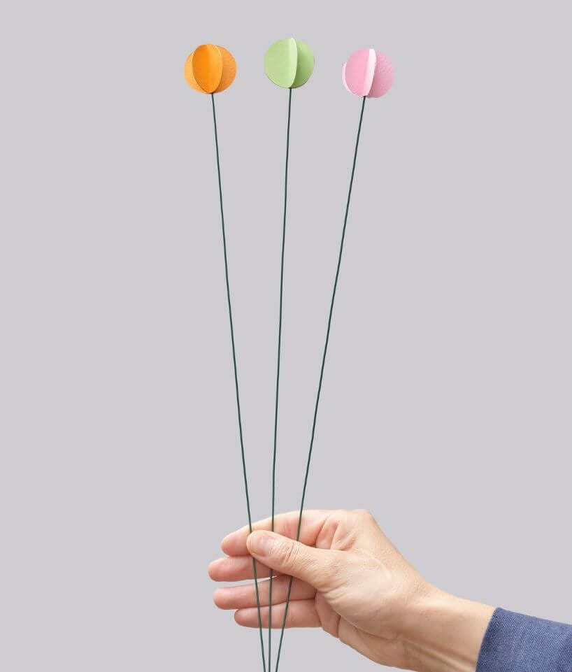 Flores individuales de papel en colores sostenidas con la mano, diseño de Cartoncita