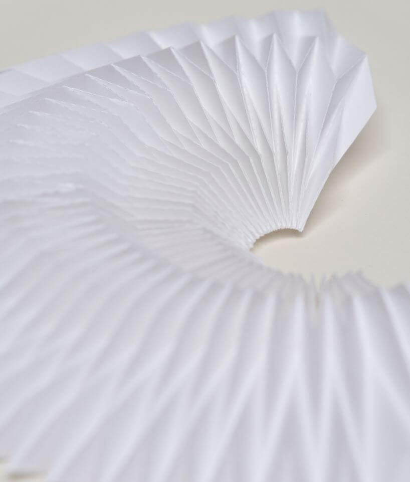 Figura semicircular de papel blanco con pliegues geométricos dispuestos en abanico, trabajo de Cartoncita